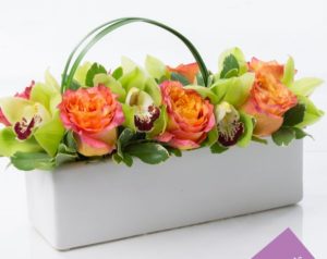 green orchids with orange roses in box